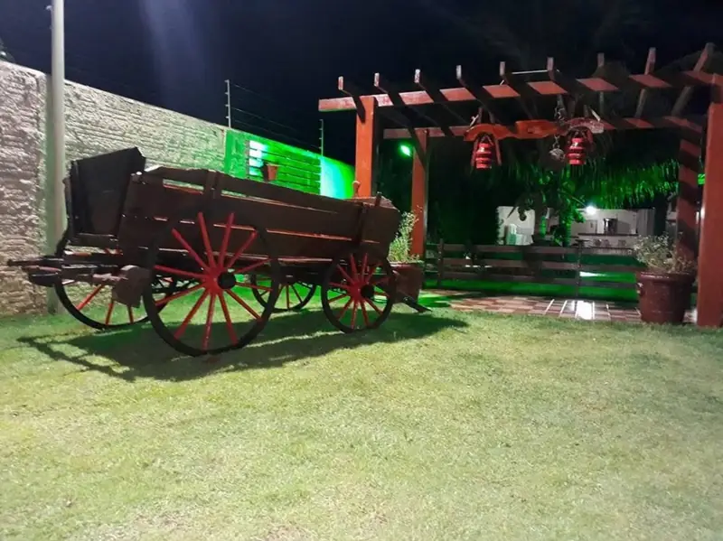 Carro de boi decorativo e pérgola no jardim iluminado à noite