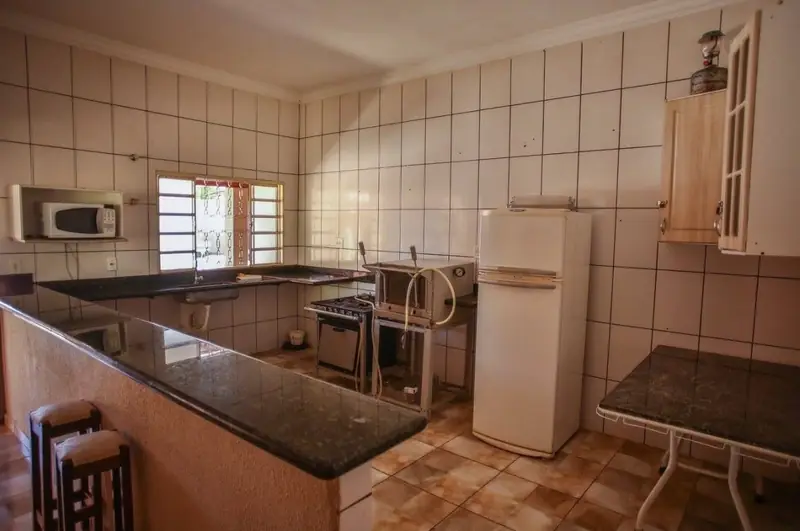 Cozinha com fogão, geladeira, micro-ondas e bancada de granito