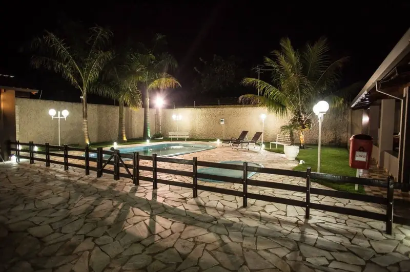 Piscina à noite com luminárias acesas e cerca de madeira