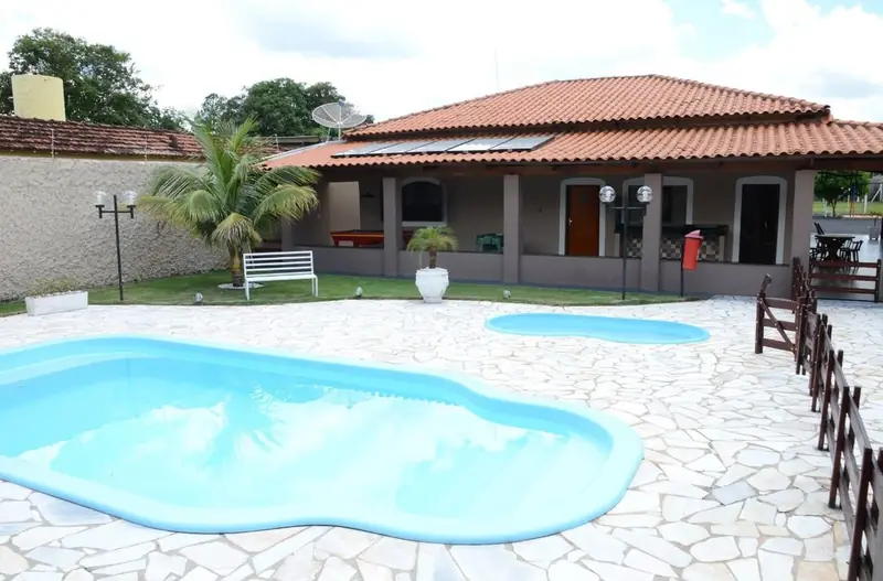 Piscina adulto e piscina infantil em frente à casa principal, com gramado e palmeira