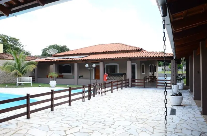 Piscina cercada por deque de pedra com a casa principal ao fundo