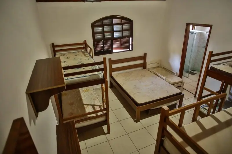 Suíte com beliches, cama de casal e banheiro com box de vidro ao fundo