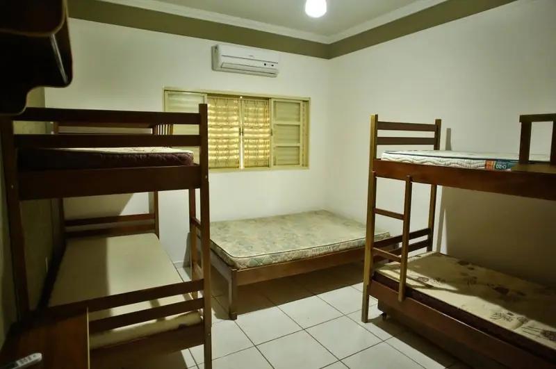 Suíte com cama de casal entre dois beliches de madeira e ar-condicionado