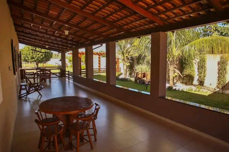 Varanda com mesa redonda de madeira, cadeiras e vista para o jardim